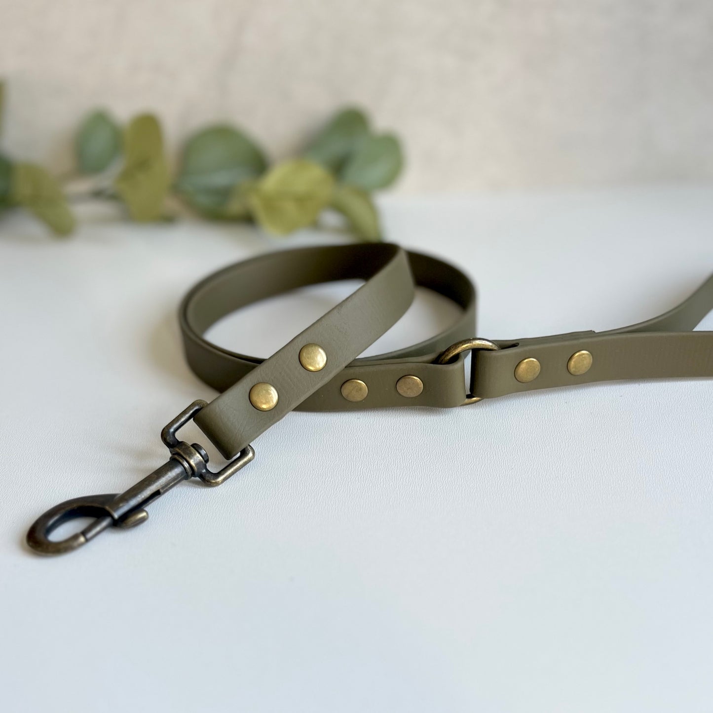 Military Olive Green Biothane lead with Antique Brass Hardware. An O-ring connects the handle to the lead with double ended rivets fixing it together. A Snap Clip is fixed with double ended rivets. The lead has a soft leather appearance.