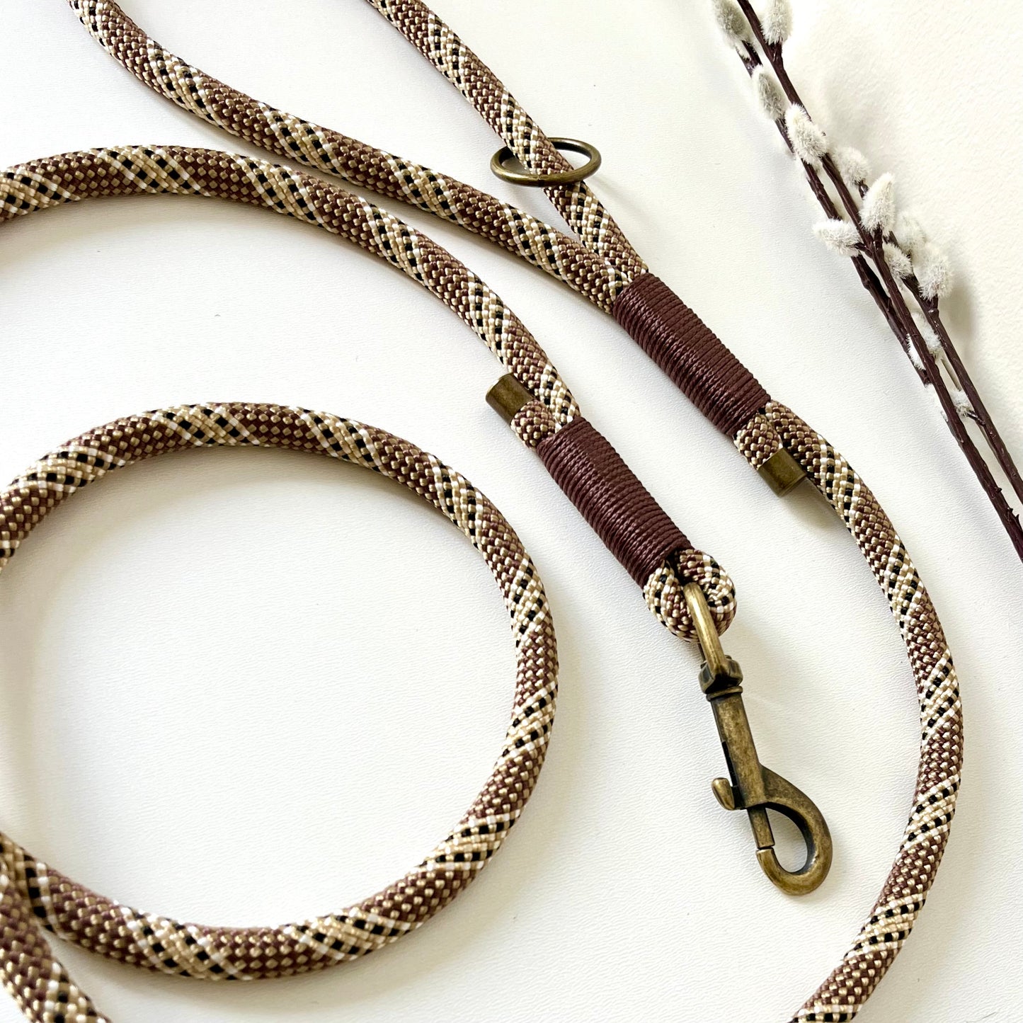 Brown rope dog lead with binding and antique brass hardware on a white surface