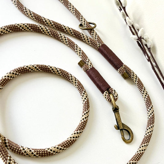 Brown rope dog lead with binding and antique brass hardware on a white surface
