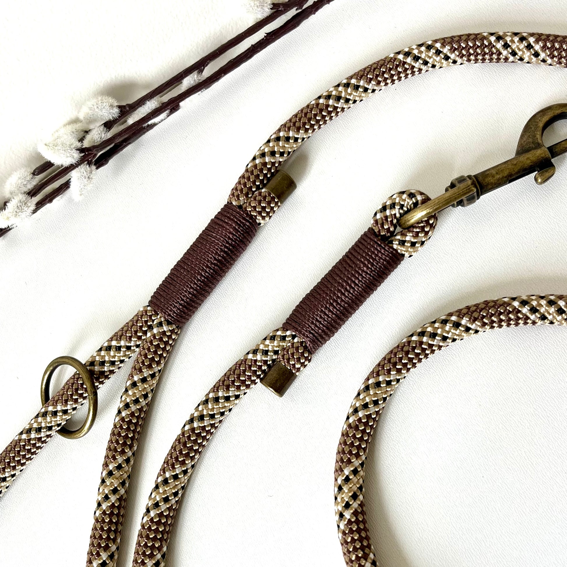 Brown rope dog lead with binding and antique brass hardware on a white surface