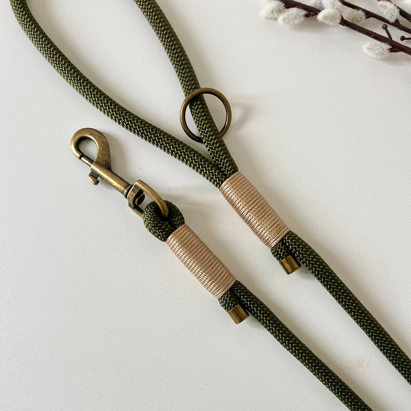 olive rope dog lead with gold binding and antique brass hardware sitting on a white surface