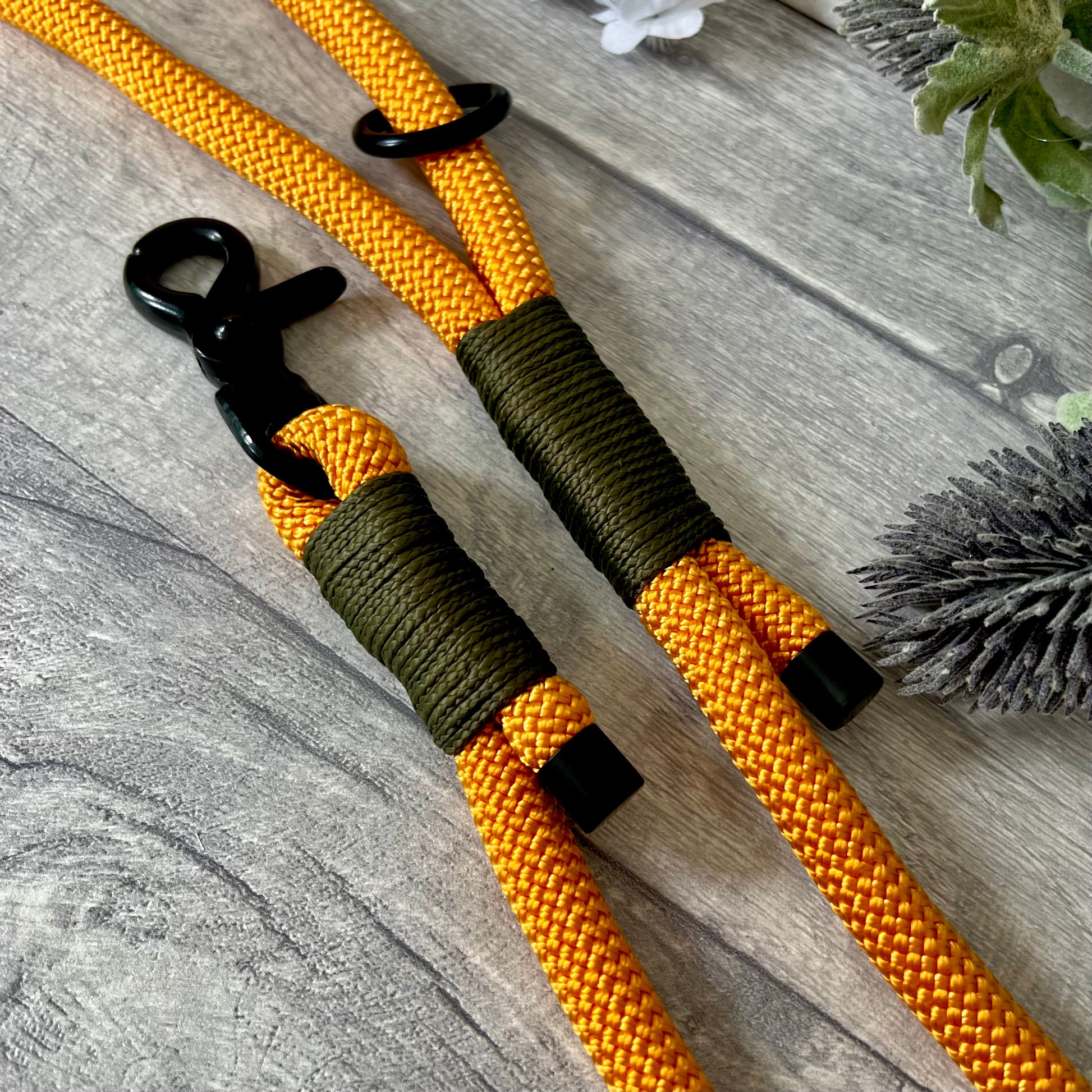 Orange rope lead with Military Green whipping securing a swivel clip at one end and fastening a handle at the other. The handle has an O-ring attached. Each end of the rope is finished with a metal end cap. All hardware for this lead is in Black