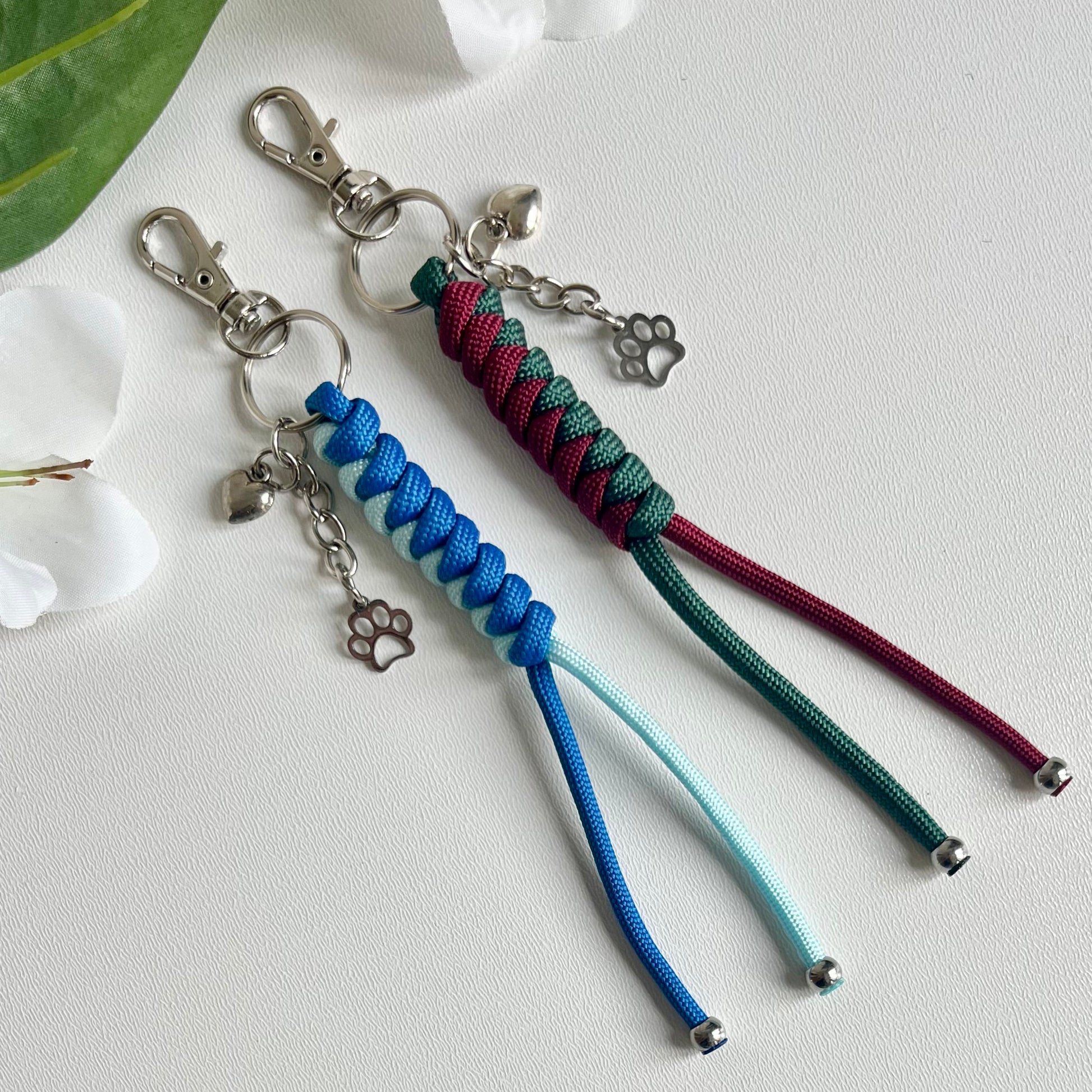 Two Paracord keychains with a heart and a paw charm on a white background