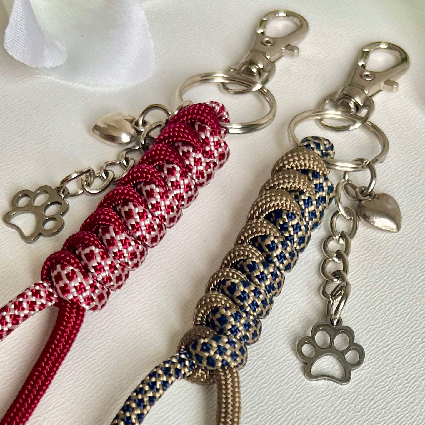Two Paracord keychains with a heart and a paw charm on a white background
