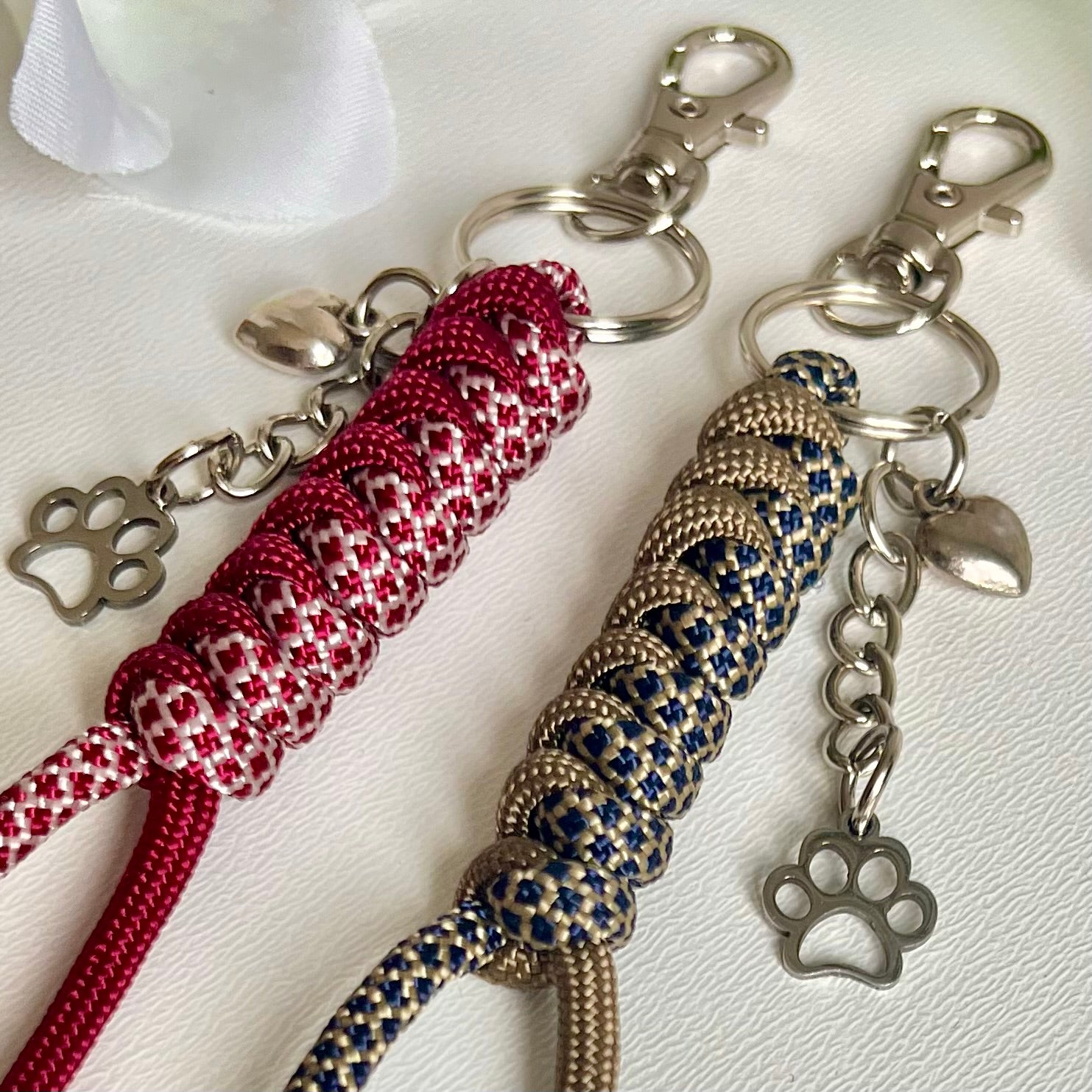 Two Paracord keychains with a heart and a paw charm on a white background