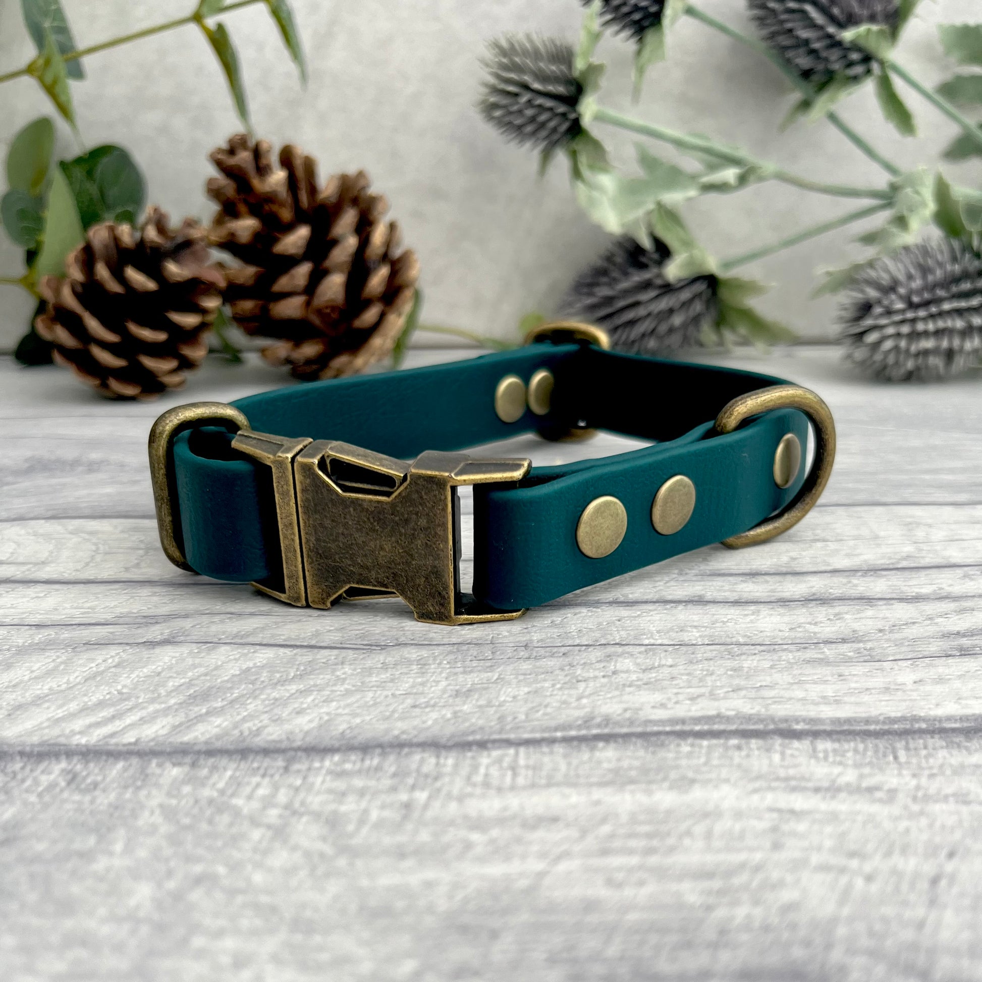 Made from Biothane in Dark Green, the collar is fastened with a metal quick release buckle, metal rivets with a metal strap keeper on one side with a D-ring on the other. All hardware is in Antique Brass