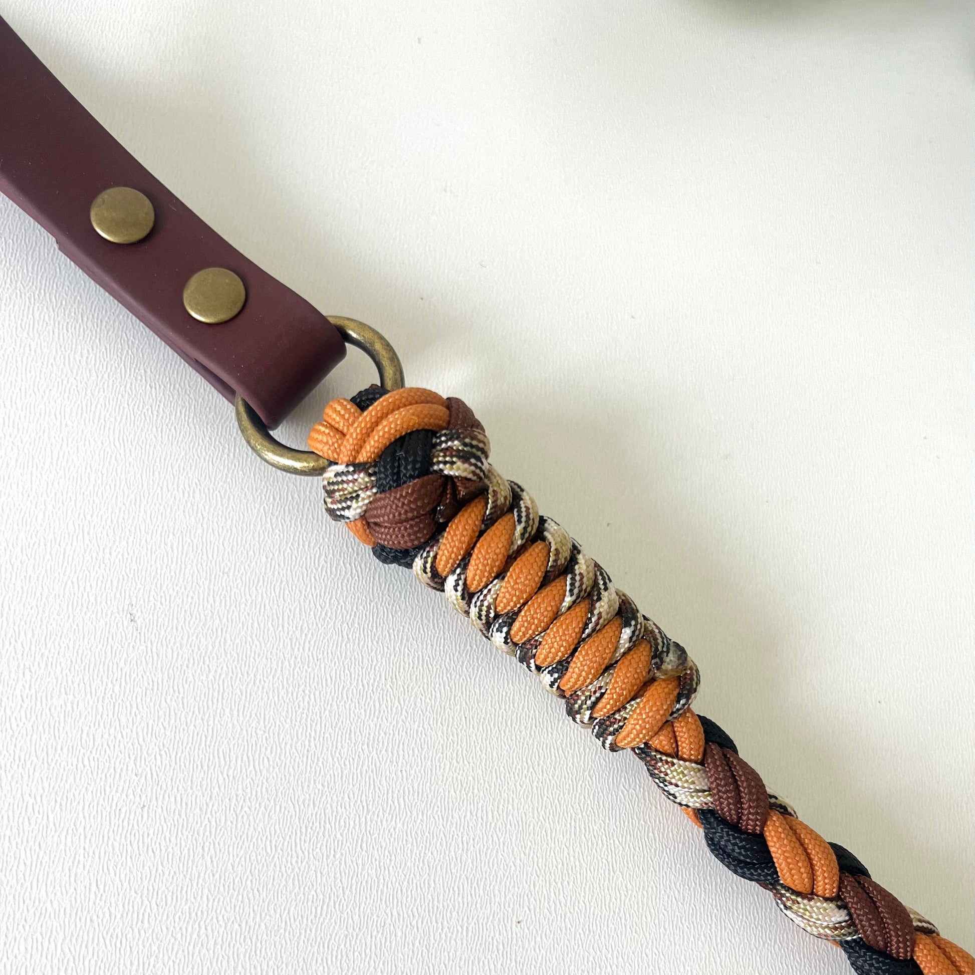 Braid rope dog lead with metal rind attached to a biothane handle in brown
