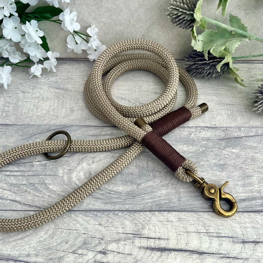 Tan rope dog lead with Brown whipping securing a swivel clip at one end with whipping securing a handle at the other. The ends of the rope ends are finished with metal end caps. All hardware is in Antique Brass