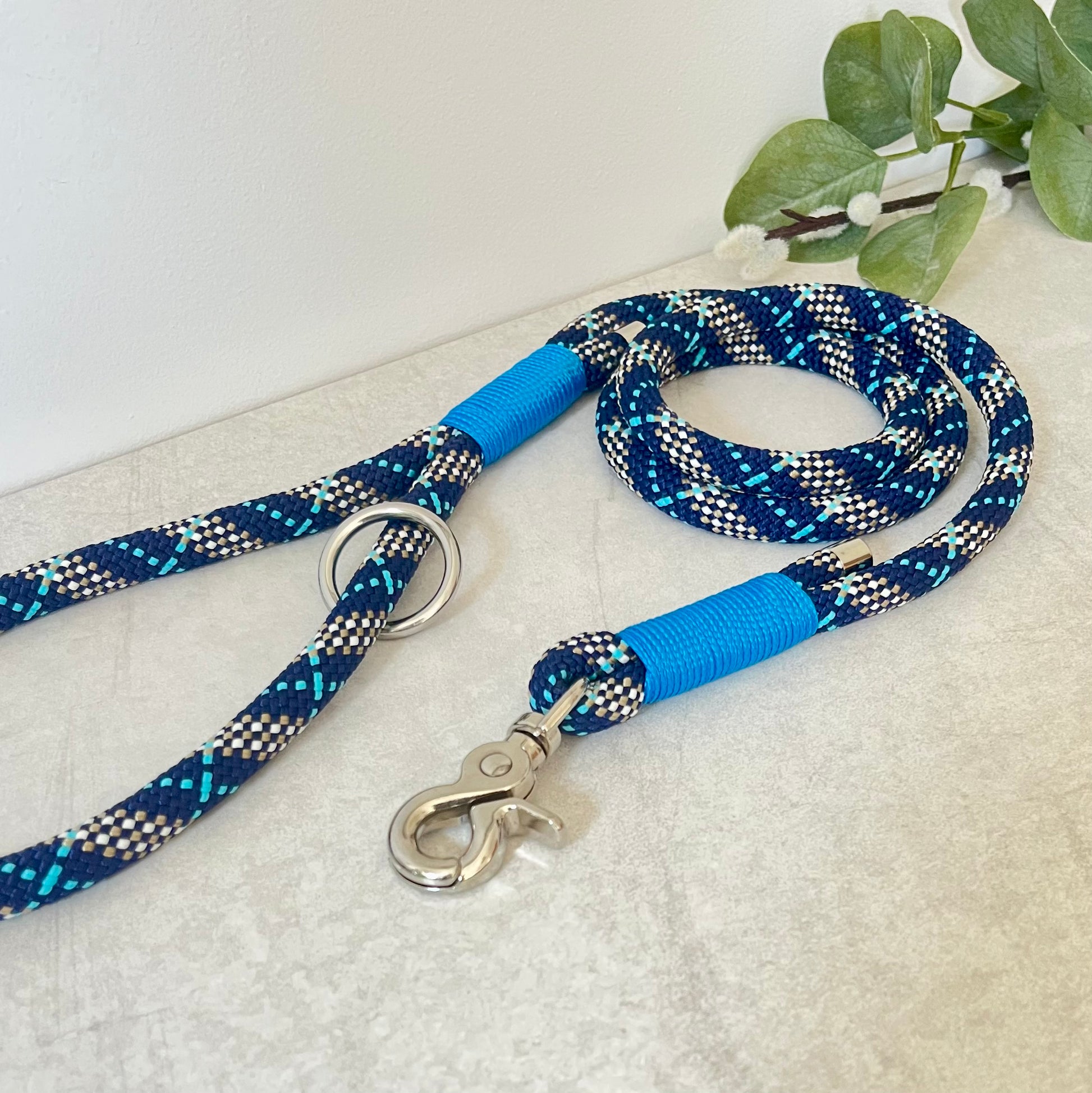 Tartan Blue rope lead with Royal Blue whipping securing a swivel clip at one end and fastening a handle at the other. The handle has an O-ring attached. Each end of the rope is finished with a metal end cap. All hardware for this lead is in Silver