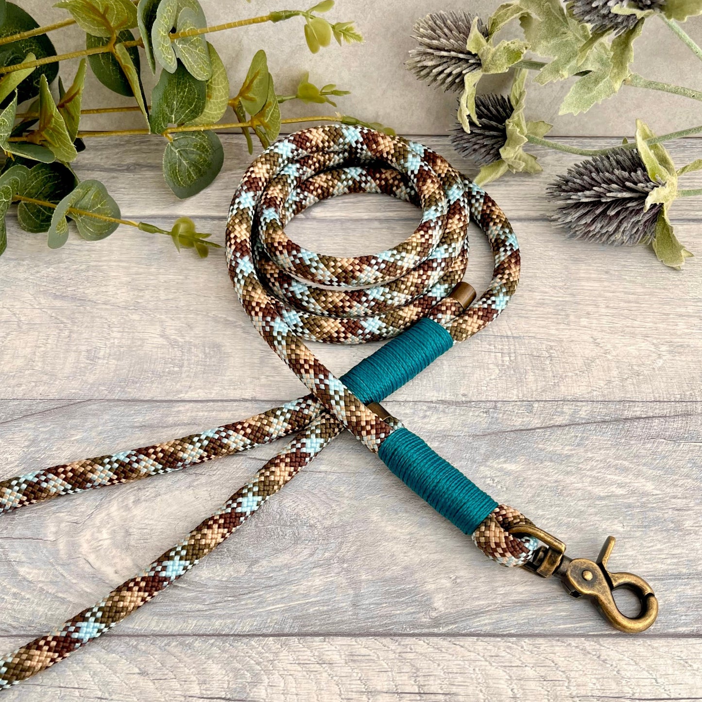 Tundra, Brown & Blue rope dog lead with Aqua whipping securing a swivel clip at one end and fastening a handle at the other. The handle has an O-ring attached. Each end of the rope is finished with a metal end cap. All hardware for this lead is in Antique Brass