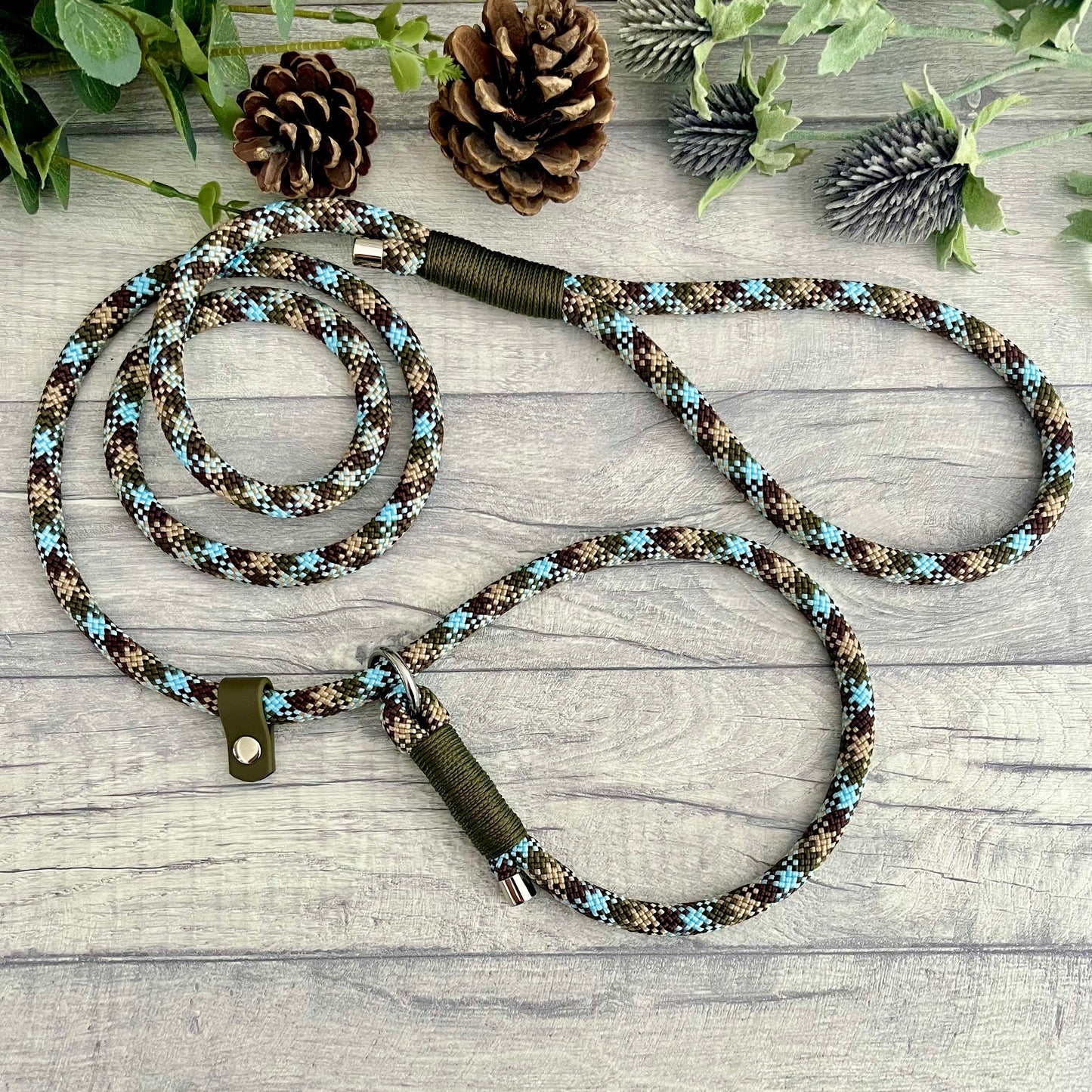 Tundra paracord slip lead. military green whipping tied fixing a O-ring loop at one end and a handle with O-ring attached at the other end. A Biothane stop in Olive is attached with metal end caps finish the rope ends. All hardware is in Silver.