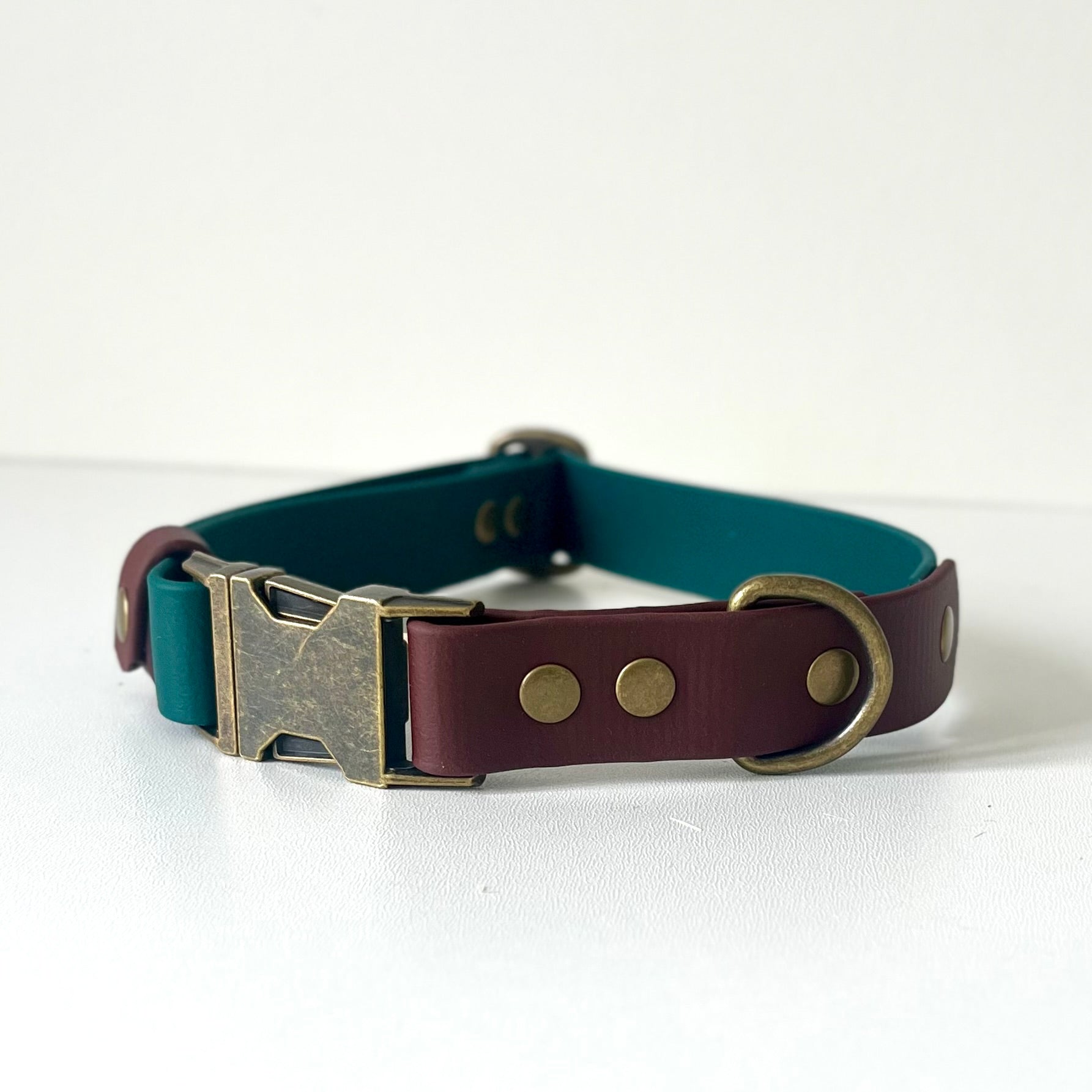 Green and brown BioThane dog collar with brass buckle on a white background